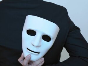 persona sosteniendo una máscara a su espalda